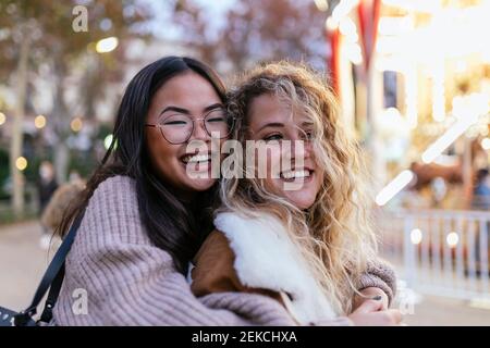 Allegre amiche che abbracciano al parco divertimenti Foto Stock