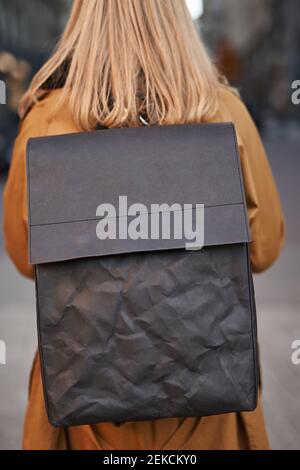 Zaino in carta nera senza sprechi su una trincea bionda di colore arancione. Concetto di carta eco moda o sacchetti zero rifiuti Foto Stock