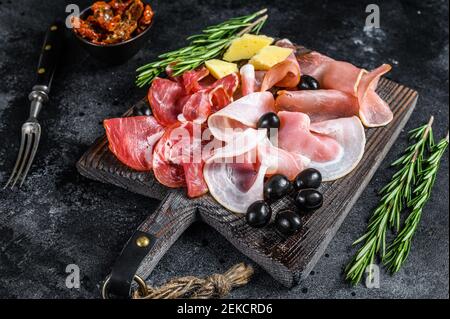 Set di carne affumicata e secca prosciutto, carne saltata, jamon ed erbe. Sfondo nero. Vista dall'alto Foto Stock