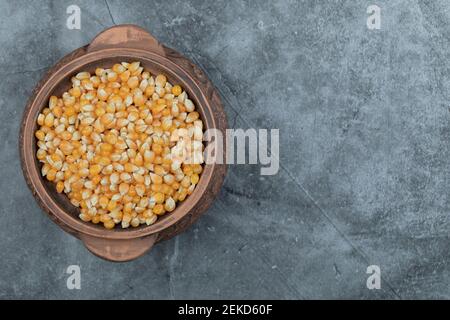 Antica pentola piena di popcorn crudo su sfondo grigio Foto Stock
