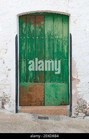 vecchia porta di legno verniciata verde in un muro di pietra dentro sud in spagna Foto Stock