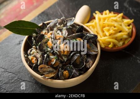 Cozze scozzesi coltivate a corda acquistate da un supermercato Waitrose che sono state cotte e aromatizzate con burro, pepe, crema, foglie di alloro, timo, onio Foto Stock