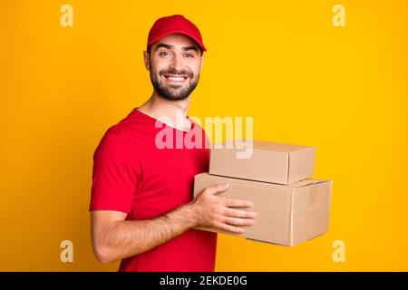 Profilo ritratto vista laterale di piacevole soddisfare allegro ragazzo mailman tenendo in mano pacchi veloci portare isolato su giallo brillante sfondo a colori Foto Stock