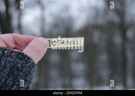 Mi piace il concetto di viaggio. Una mano tiene un segno con l'iscrizione sullo sfondo della foresta invernale. Foto Stock
