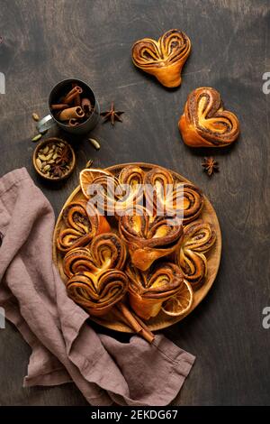 Dolci rotoli di cannella fatti in casa a forma di cuore in un vecchio stile retrò. Umore di Capodanno. Tradizionali cinnaboni svedesi. Messa a fuoco selettiva Foto Stock