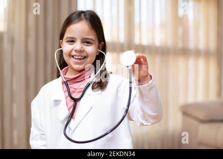 Ritratto di bambino sorridente vestito da medico con stetoscopio in mano. Concetto di salute e benessere. Spazio per il testo. Foto Stock