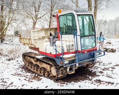 Dumper cingolato con paraurti piccolo con telaio fangoso. Il trasportatore in attesa nella foresta innevata Foto Stock