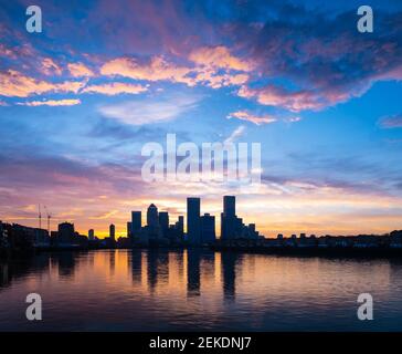 Spettacolare alba su Canary Wharf, capitale finanziaria del Regno Unito, Londra con il fiume Tamigi in primo piano che riflette il cielo viola e giallo Foto Stock