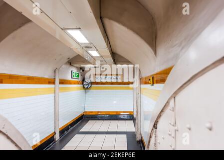 Londra, UK stazione metropolitana corridoio sotterraneo corridoio con nessuno e indicazioni per i treni con colore giallo arancione Foto Stock