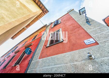 Chiusi, via Italia che guarda in alto la vista nel piccolo borgo storico medievale in Umbria con rosso giallo luminoso vivace mura dipinte colorate Foto Stock