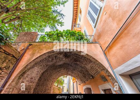 Chiusi, Italia strada in piccolo borgo storico medievale in Toscana estate con nessuno arancio colorato muro e arco volta passaggio Foto Stock
