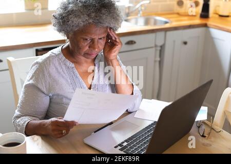 Ha sottolineato la donna anziana afroamericana usando il laptop e calcolando le finanze a casa Foto Stock