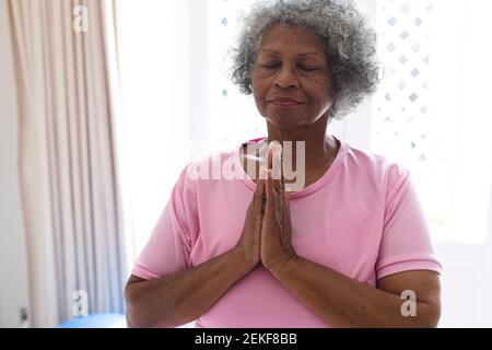 Donna anziana afroamericana che pratica yoga e meditating a casa Foto Stock