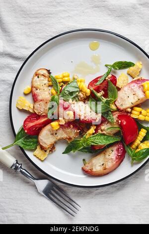 Insalata estiva con pesche alla griglia, mais, pomodori freschi e basilico. Foto Stock