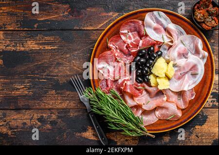 Piatto di carne italiana con prosciutto, bresaola, pancetta, salame e parmigiano. Sfondo di legno scuro. Vista dall'alto. Spazio di copia Foto Stock