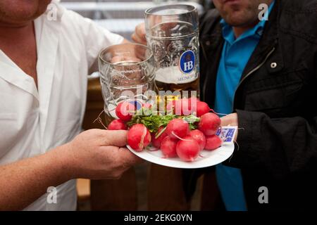 Germania i festeggiatori di Monaco celebrano l'Oktoberfest (Oktoberfest) all'interno delle tende di Theresienwiese. Qui mangiano ravanelli. Foto Stock