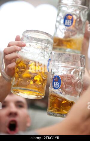 Germania i festeggiatori del Munch celebrano l'Oktoberfest (Oktoberfest) all'interno delle tende sopra Theresienwiese.Holding up tazze di birra e tostatura Foto Stock