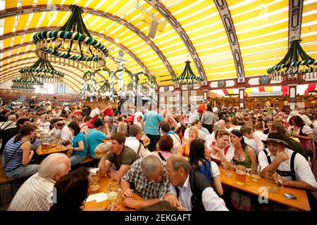 I festaioli all'interno della tenda di Lowenbrau a ottobre sul Theresienwiese A Monaco Foto Stock