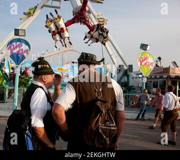 Germania Munich Octoberfest (Oktoberfest) : due uomini anziani a Lederhosen guardare una delle giostre Foto Stock