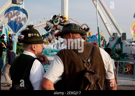 Germania Munich Octoberfest (Oktoberfest) : due uomini anziani a Lederhosen guardare una delle giostre Foto Stock