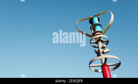 Generazione di energia elettrica mentre la turbina eolica ad asse verticale gira contro cielo blu Foto Stock