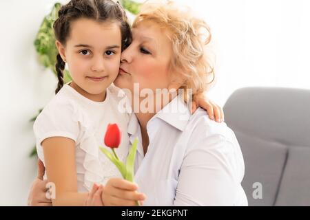 Congratulazioni concetto. Congratulazioni per la vacanza. La nipote dà il fiore a sua nonna l'8 marzo. Giornata internazionale della donna Foto Stock