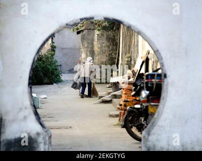 Donna al lavoro come spazzatrice di strada in una strada in un hutong di Pechino, Cina Foto Stock