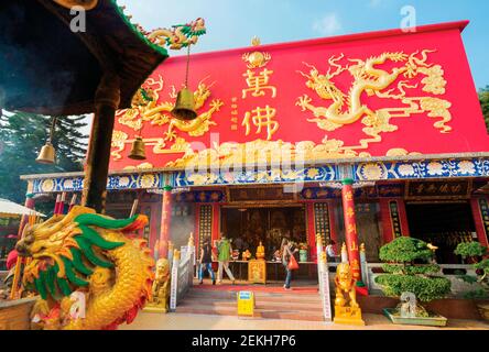 Hong Kong, Cina. Visitatori all'ingresso del monastero dei diecimila Buddha di Pai Tau Tsuen, Sha Tin, nei nuovi territori. Foto Stock