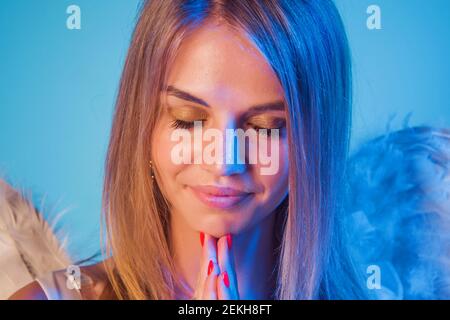 Angelo donna con ali bianche. Giorno di San Valentino Cupido. San Valentino. Ragazza angelo in preghiera. Foto Stock