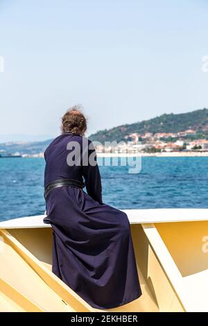 Il vecchio monaco guarda le montagne Athos su una nave in una giornata estiva Foto Stock