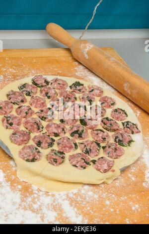 Cottura di gnocchi fatti in casa in forma rotonda. Carne tritata con spinaci su pasta sottile arrotolata. Primo piano, messa a fuoco selettiva. Foto Stock