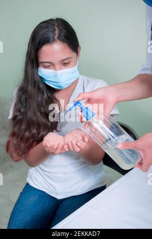 adolescente che mette gel antibatterico sulle mani Foto Stock