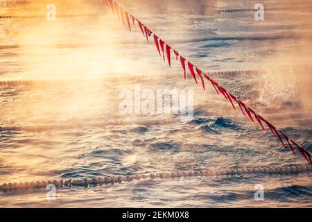 Corsie e bandiere in piscina con nebbia sull'acqua. Concorso sportivo. Foto Stock