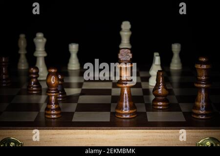 Scacchiera in legno e pezzi con sfondo nero. Foto Stock