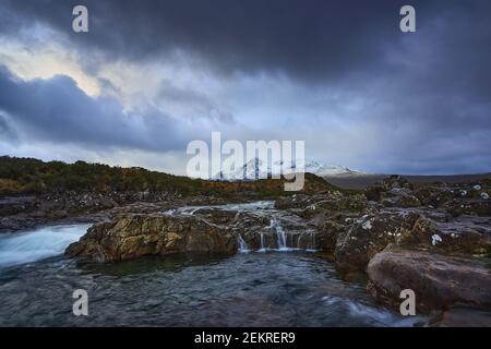 Lunga esposizione di acqua su rocce e piccola cascata su Il fiume Sligachan sull'isola di Skye Scozia con La catena montuosa di Cuillin nella dista Foto Stock