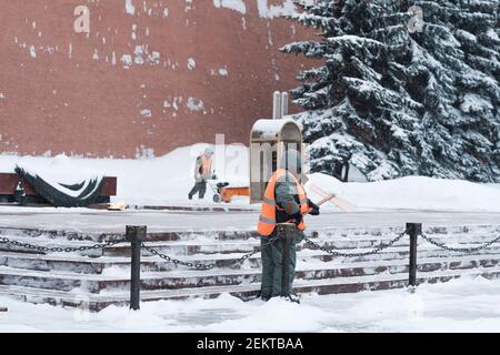 Mosca. Russia. 12 febbraio 2021. Gli addetti alle utenze rimuovono la neve con un soffiatore di neve e pale durante una nevicata vicino al muro del Cremlino nella tomba di Foto Stock