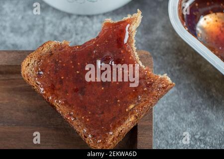 Una fetta di pane marrone con marmellata di fragole Foto Stock