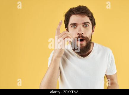 Uomo bearded che tiene le mani vicino al viso su sfondo giallo primo piano vista ritagliata Foto Stock