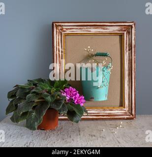Ancora vita con violette in fiore e un secchio di fiori bianchi in una cornice di legno. Vintage. Foto Stock