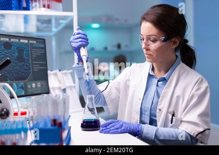 Scienziato professionista che prende campione per esperimento medico. Ricercatore chimico che lavora in laboratorio con micropipetta per scoprire il vaccino contro il coronavirus. Foto Stock