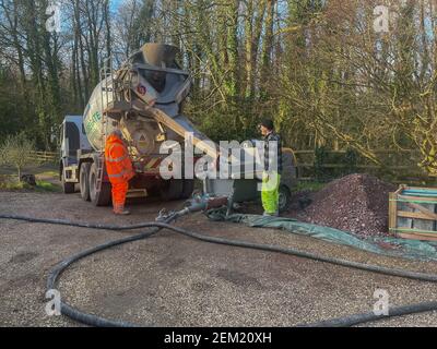 Scaricare il rasatore per pavimenti liquidi da un camion betoniera in una pompa di flusso in un cantiere edile nella provincia di Devon, Inghilterra, Regno Unito Foto Stock