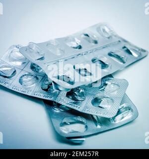 Più confezioni blister di capsule trasparenti disposte su uno sfondo chiaro in ambiente clinico Foto Stock