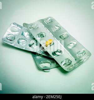 Più confezioni blister di farmaci con una pillola mancante, visualizzate sotto un'illuminazione soffusa per un effetto clinico Foto Stock