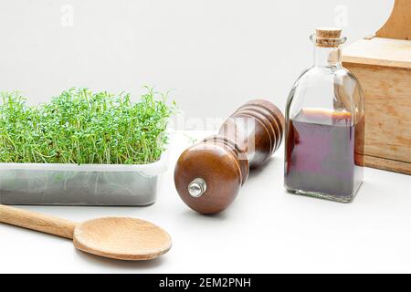 Micro verde crescione germinato a casa e olio di semi di zucca in una bottiglia sul tavolo da cucina, cibo sano e concetto di supercibo Foto Stock