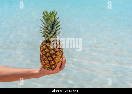 L'uomo tiene l'ananas sullo sfondo del mare. Concetto di vacanza e viaggio. Foto Stock