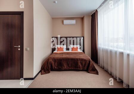 Interno di una confortevole camera da letto d'hotel al mattino in stile lussuoso. Grande finestra Foto Stock