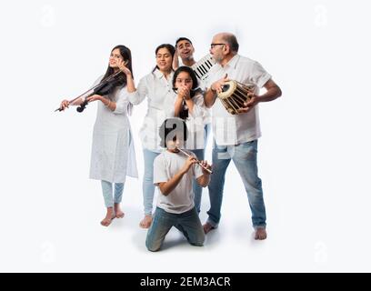 Concerto di una famiglia indiana di sei strumenti musicali in un gruppo e una donna anziana che canta, in piedi su sfondo bianco Foto Stock
