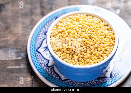 Primo piano del ptitim secco. Pasta tostato pittim (petit plomb o couscous israeliano) su sfondo di legno Foto Stock