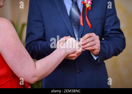 Lo sposo mette sull'anello di nozze della sposa. Foto Stock