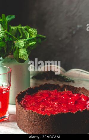 Composizione sorprendente con cheesecake alla fragola e bevanda alla fragola con rosmarino. Solo una parte della cheesecake a fuoco e una particella di un bicchiere di d Foto Stock